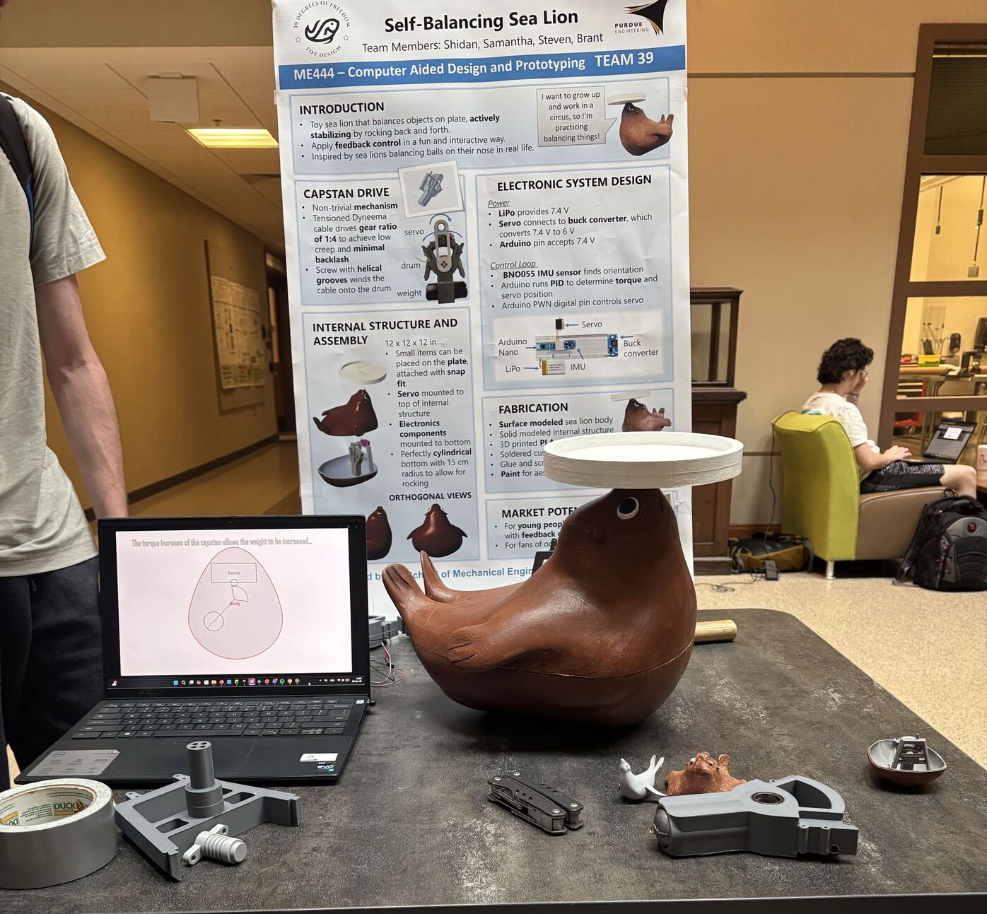 Demo day table with the poster, laptop, prototype parts, and the finished sea lion